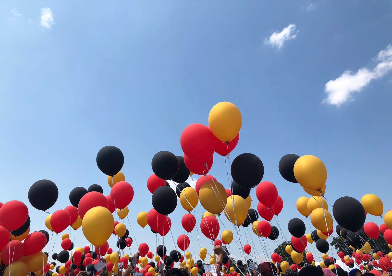 Schwarze, rote und goldene Luftballons vor blauem Himmel